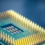 High-resolution macro shot of a computer CPU chip with gold pins against a blue background.