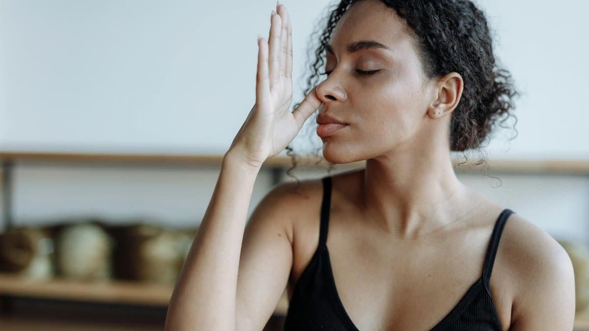 Close-up of a woman practicing yoga breathing techniques indoors, focusing on relaxation.