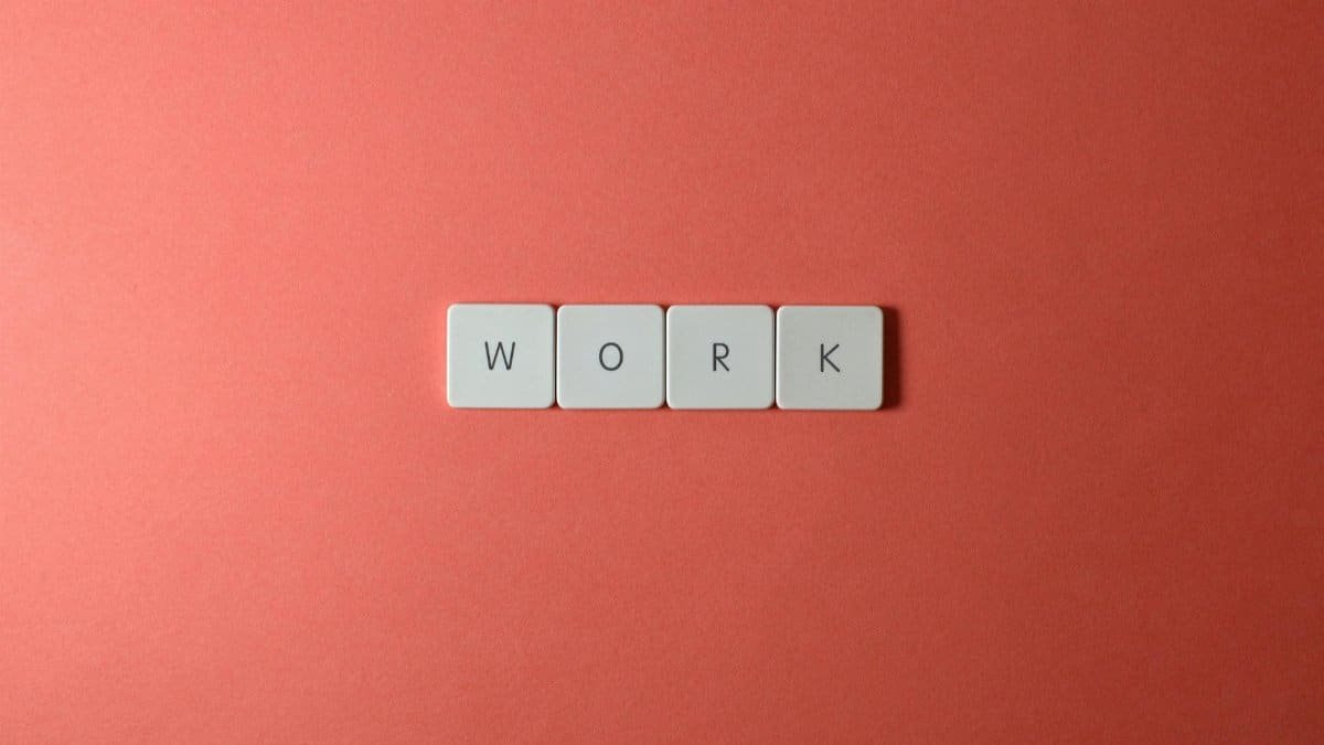 Minimalist image featuring the word 'work' with keyboard keys on a coral background. Perfect for workplace or business themes.
