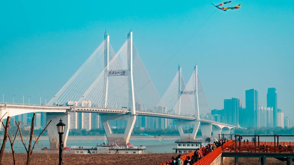 This bridge spans a river in the city, showcasing sleek architecture under a blue sky.