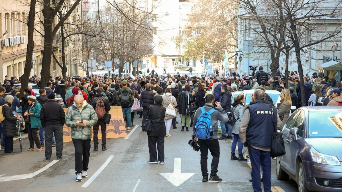 A large group of people gathered in an urban street for a city protest during the day.