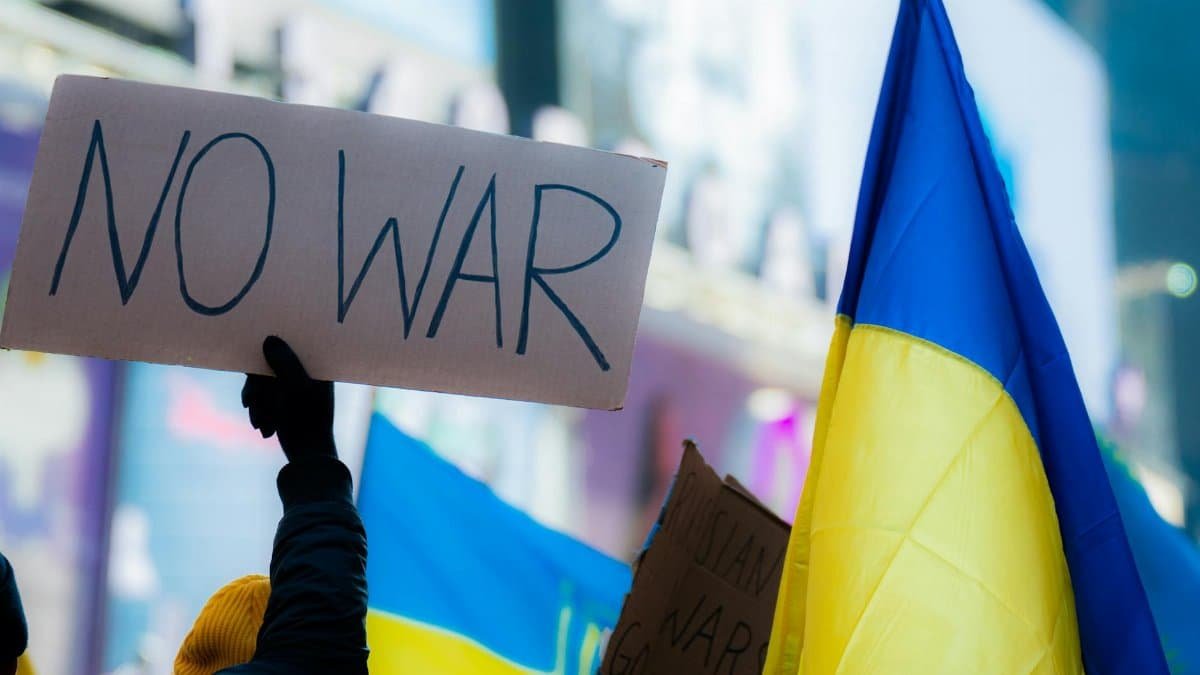 Close-up of protesters with 'No War' sign and Ukrainian flag in Times Square, New York City.