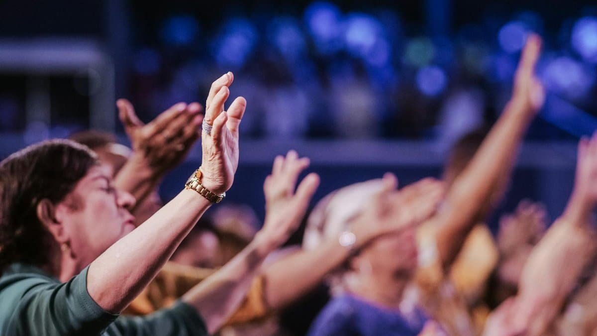 A group of people raising hands in unified prayer during a spiritual gathering.