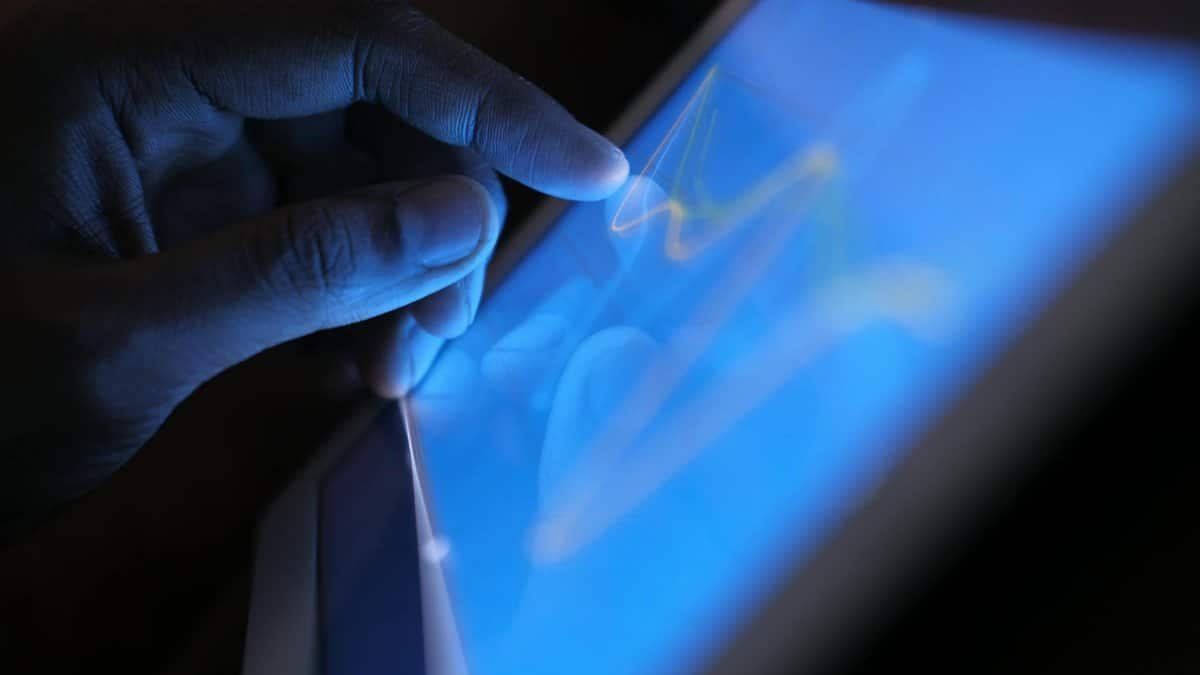 Close-up of a hand interacting with a touch screen tablet, showcasing modern technology use.