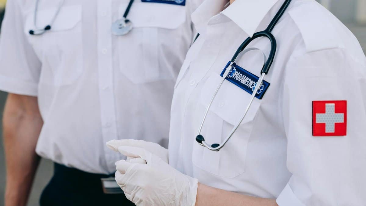 Close-up of paramedics in uniform with medical gloves and stethoscope outdoors.