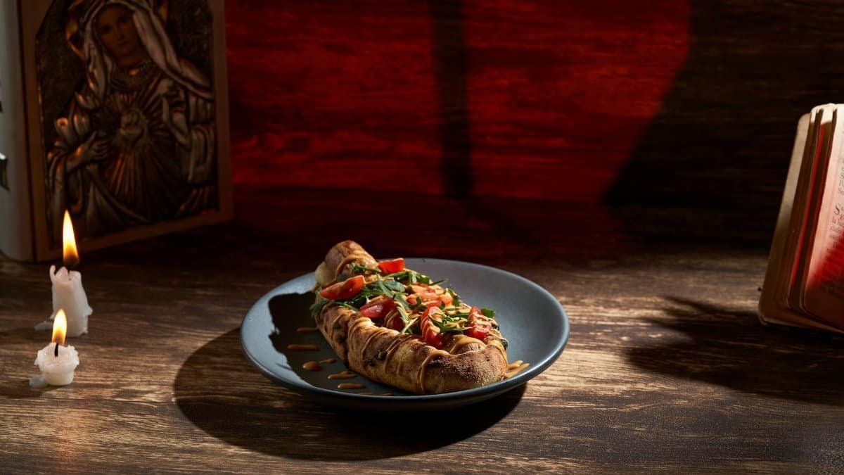 A beautifully presented bruschetta on a plate with candles and religious imagery in the background.