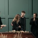 Family mourns together in solemnity at a funeral indoors.
