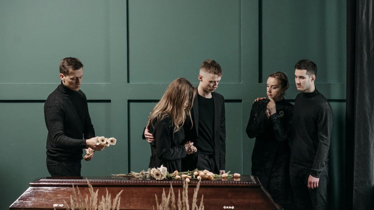 Family mourns together in solemnity at a funeral indoors.