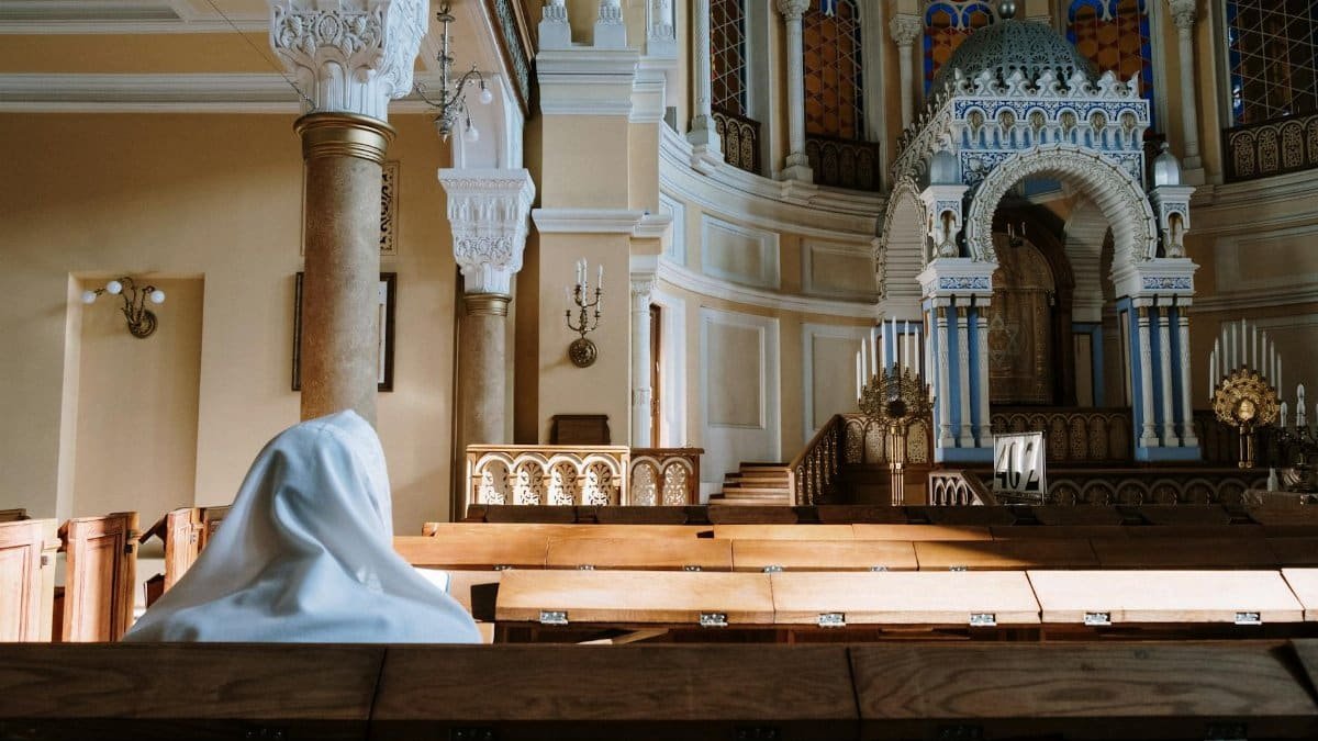 A person in tallit sits in a synagogue, capturing the serene and spiritual ambiance.