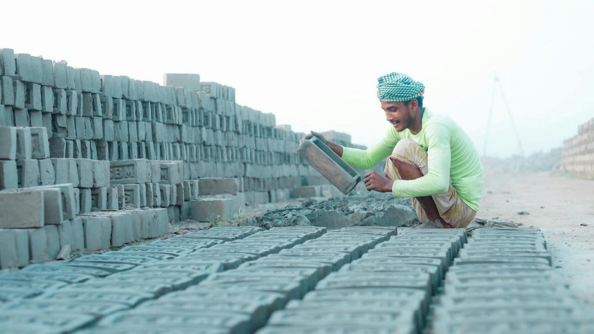 A construction worker lays bricks at an outdoor construction site.