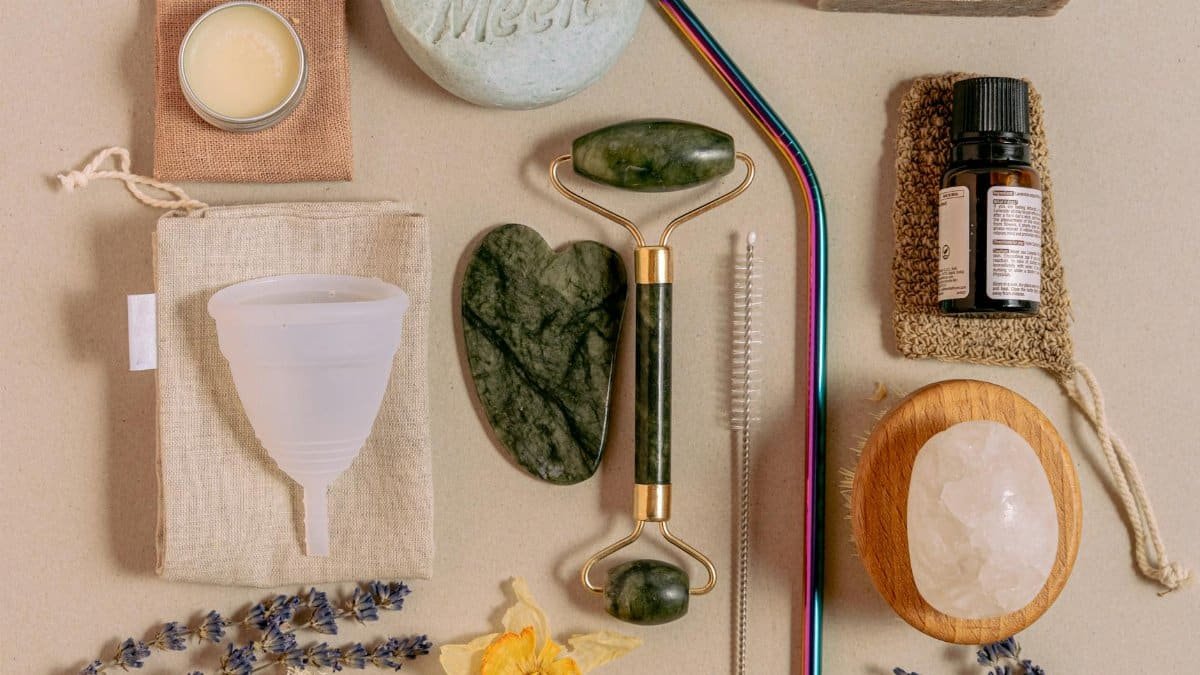 Flat lay of sustainable beauty products featuring jade roller, menstrual cup, and reusable straws.