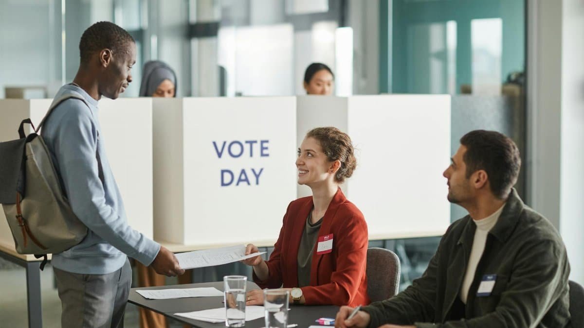 Diverse group of voters and officials at an indoor polling station on voting day.