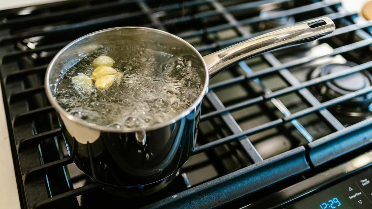 Close-up of garlic boiling in a pot on a stove, showcasing culinary preparation.