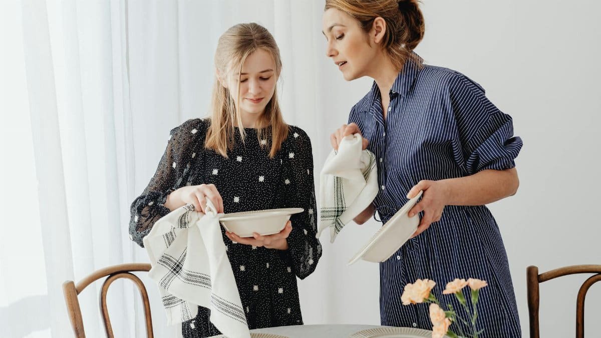 A mother and daughter teamwork in dish cleaning, fostering learning and bonding in a home setting.