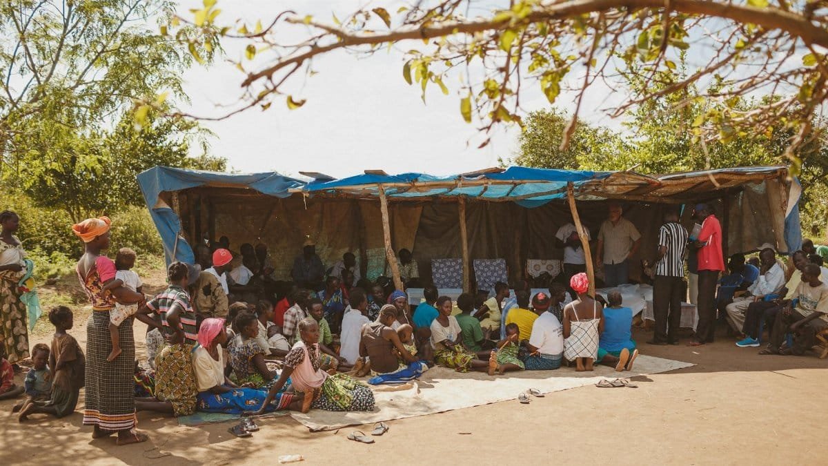 A vibrant community gathering under a tent in Kitgum, Uganda.