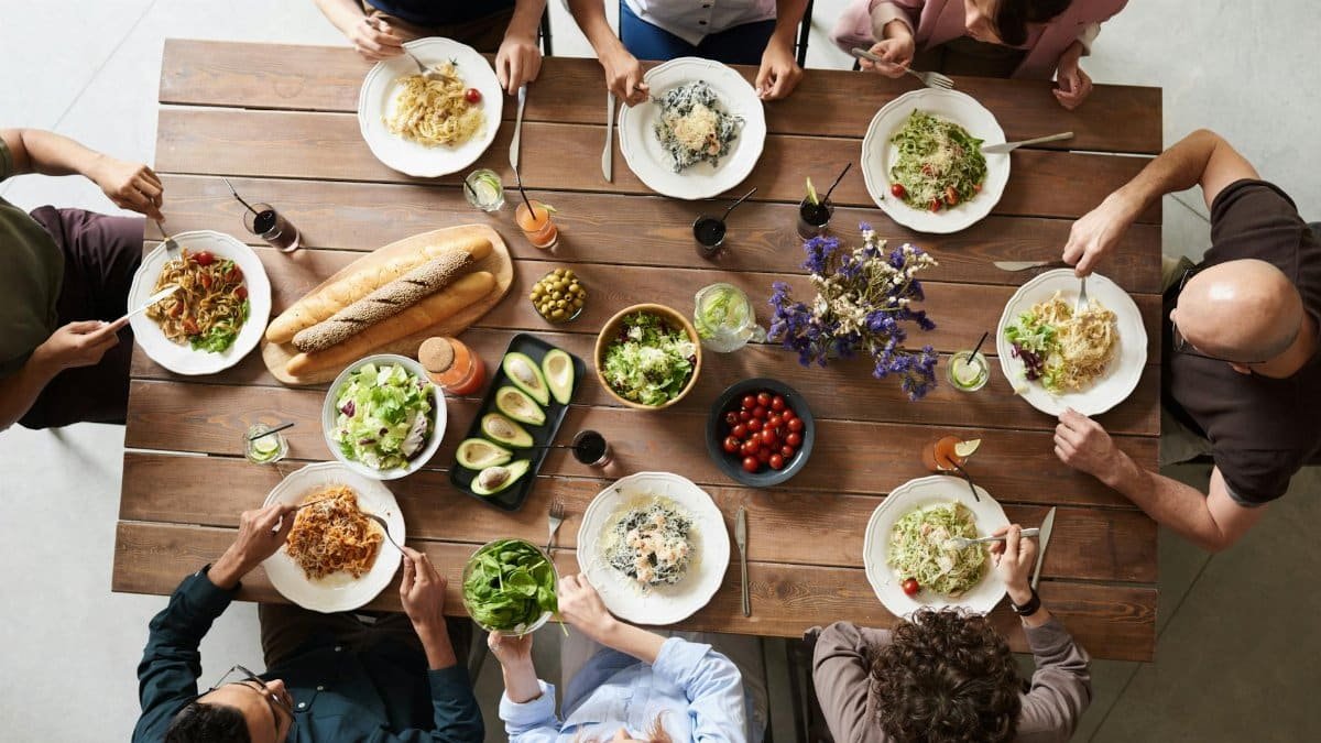 A diverse group of adults enjoying a shared meal indoors, viewed from above.