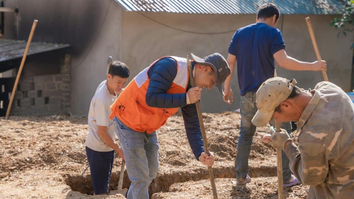 Group of workers digging foundation trenches at a construction site outdoors.