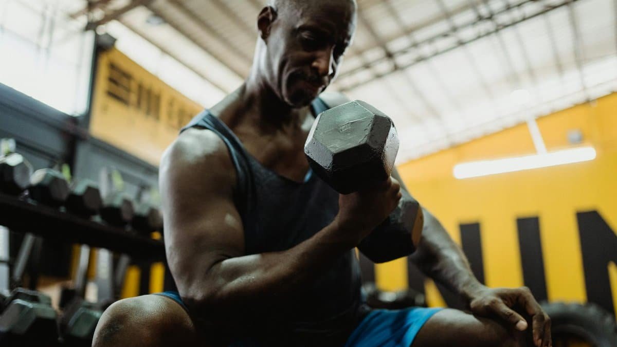 Mature man lifting dumbbell in indoor gym setting. Emphasizing strength and fitness.