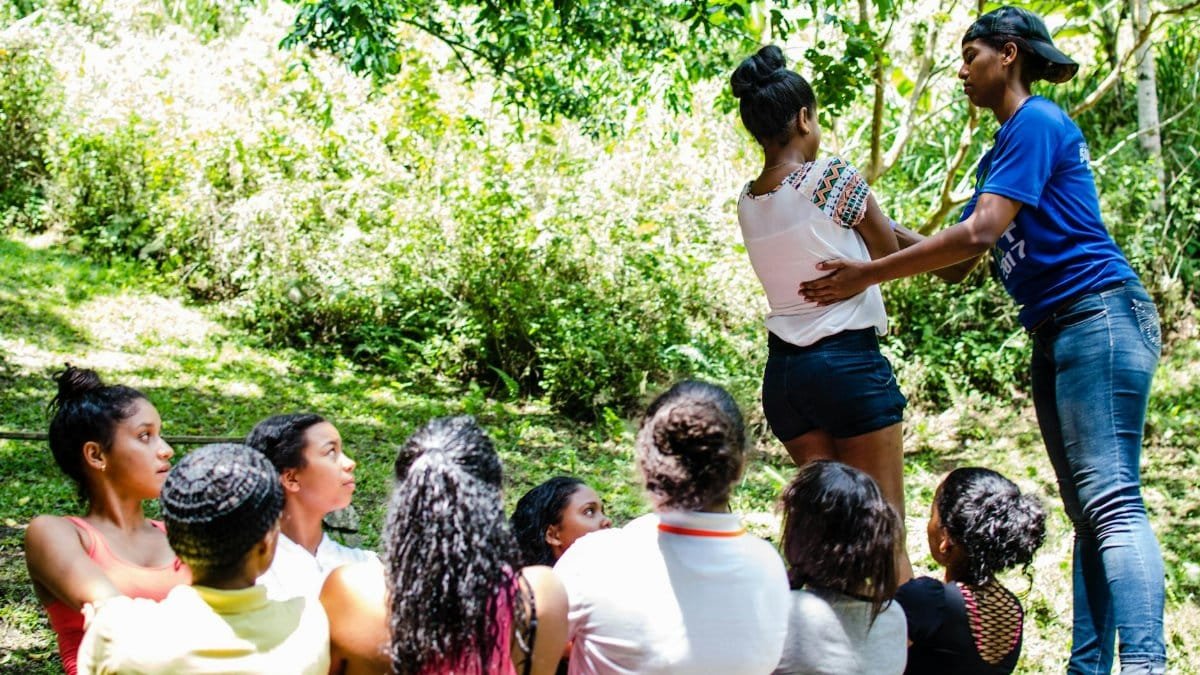 Diverse group participating in an outdoor team building exercise in a lush green setting.