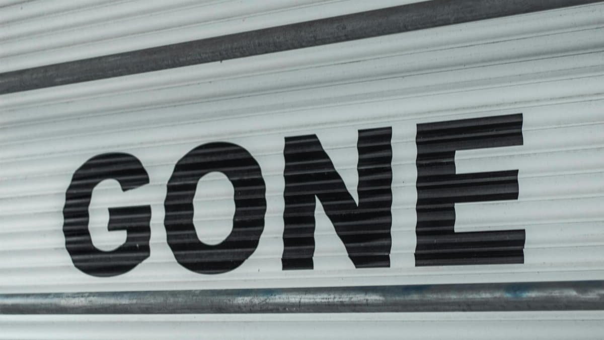Close-up of a corrugated steel shutter with bold black 'Gone' text, providing a minimalist industrial vibe.