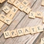 Scrabble tiles spelling 'UPDATE' on wooden surface, symbolizing progress and change.