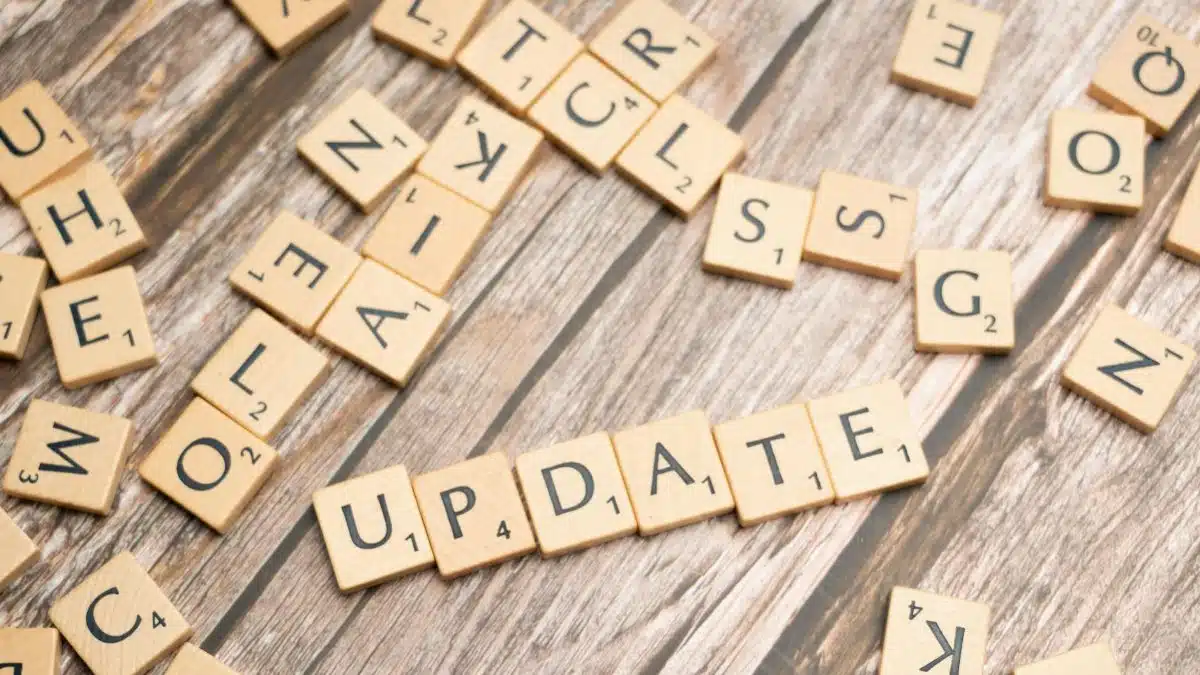 Scrabble tiles spelling 'UPDATE' on wooden surface, symbolizing progress and change.