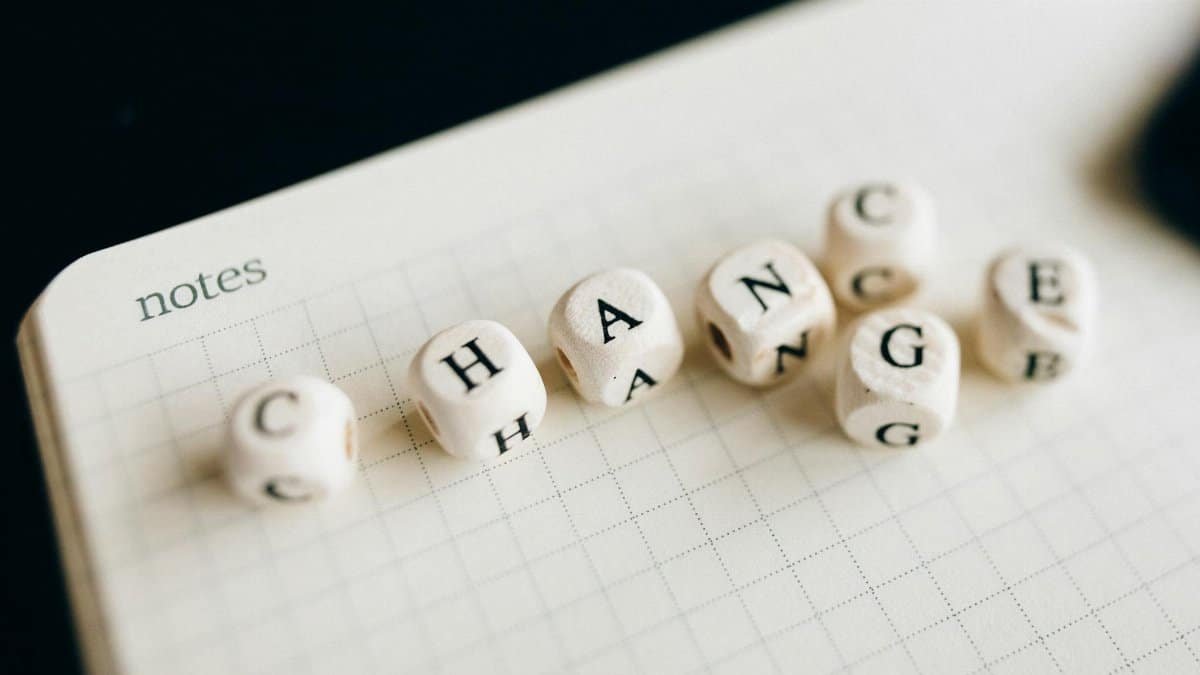 Close-up of letter dice spelling 'change' on a grid notepad, symbolizing transformation.