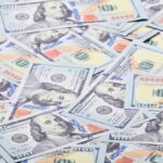 Close-up view of scattered US hundred dollar bills, showcasing paper currency.