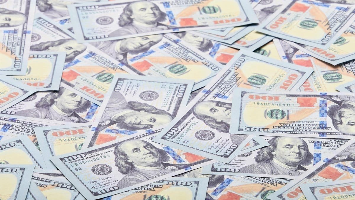 Close-up view of scattered US hundred dollar bills, showcasing paper currency.