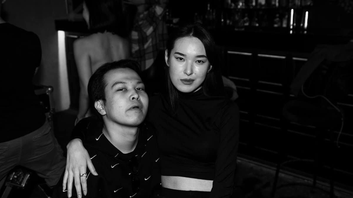 A couple sitting together in a dimly lit bar, embracing an edgy style.