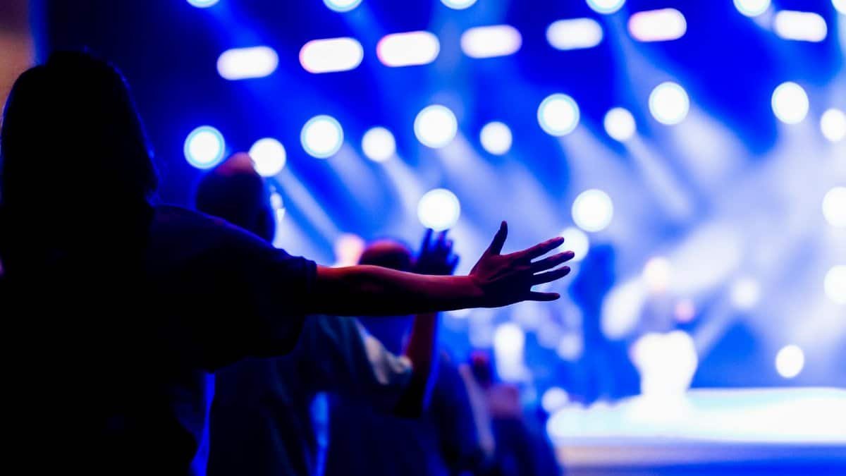 Vibrant concert scene with people raising hands, capturing the energy and spirituality of the moment.