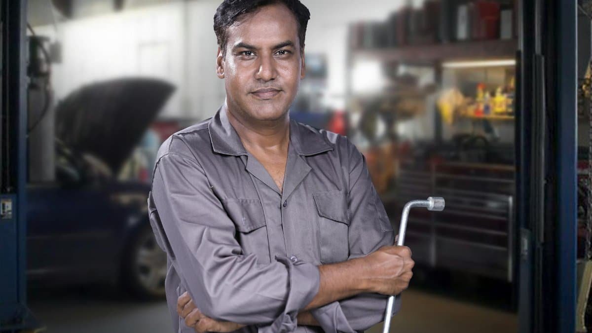 Portrait of a skilled mechanic holding a lug wrench in a Karachi auto repair shop.