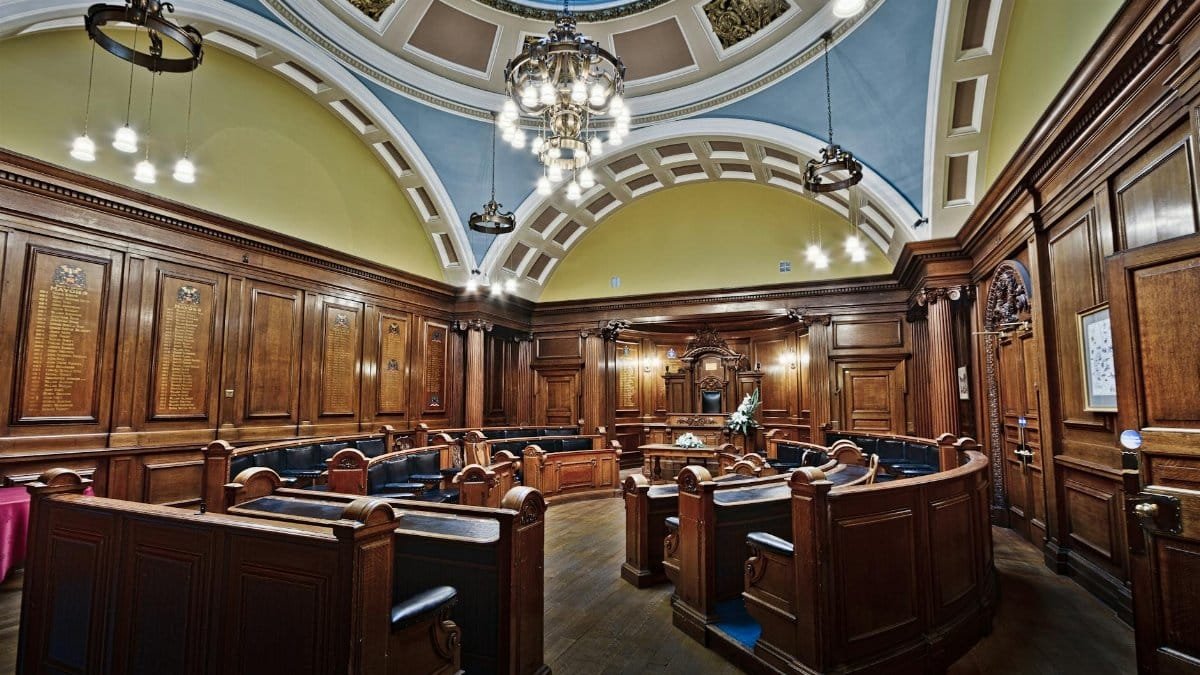 Victorian council chamber in Lancaster Town Hall with elegant wooden decor and skylight.