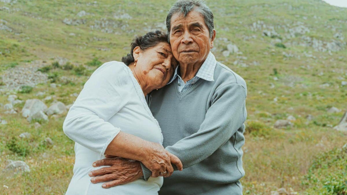 An elderly couple shares an embrace in a scenic mountain setting in Lima, Perú.