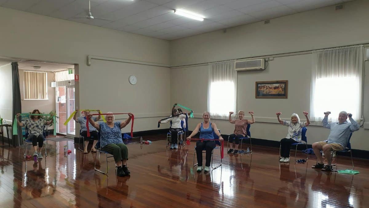 Active seniors engaging in a chair exercise class, promoting wellness and positive aging.