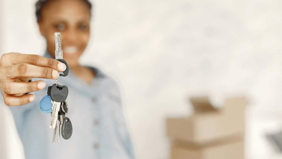 Close-up of a woman holding keys with a blurred background, symbolizing a new home or real estate concept.