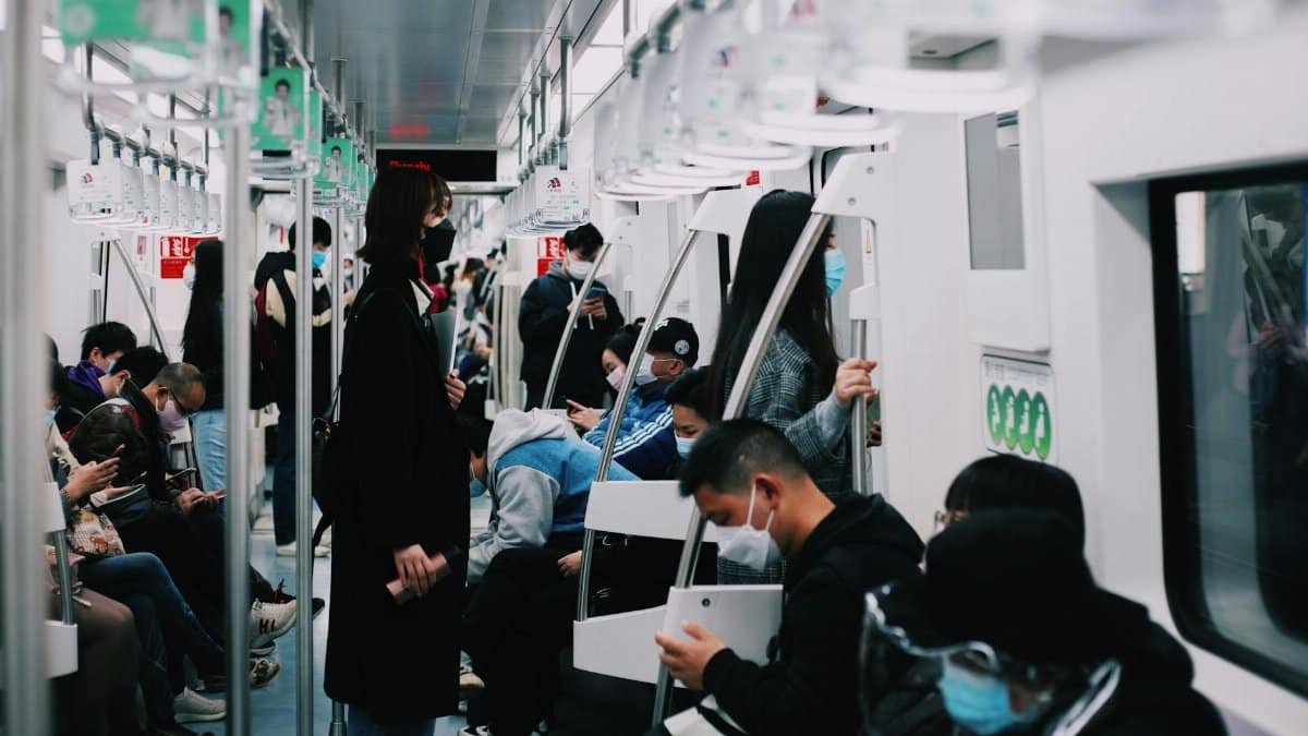 Commuters wearing masks on a subway train, reflecting pandemic public transportation usage.