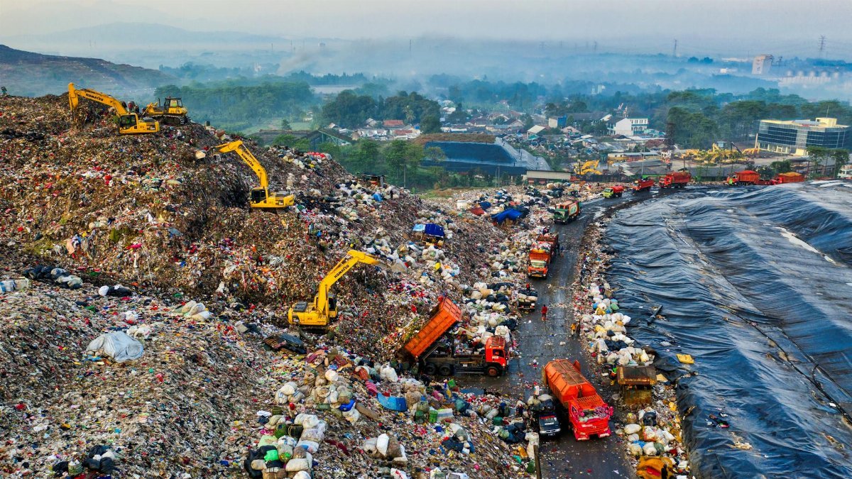 Aerial shot of a landfill with machinery in West Java, highlighting pollution and waste management challenges.