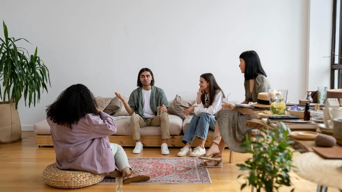 A group of diverse friends engaged in conversation in a modern living room.