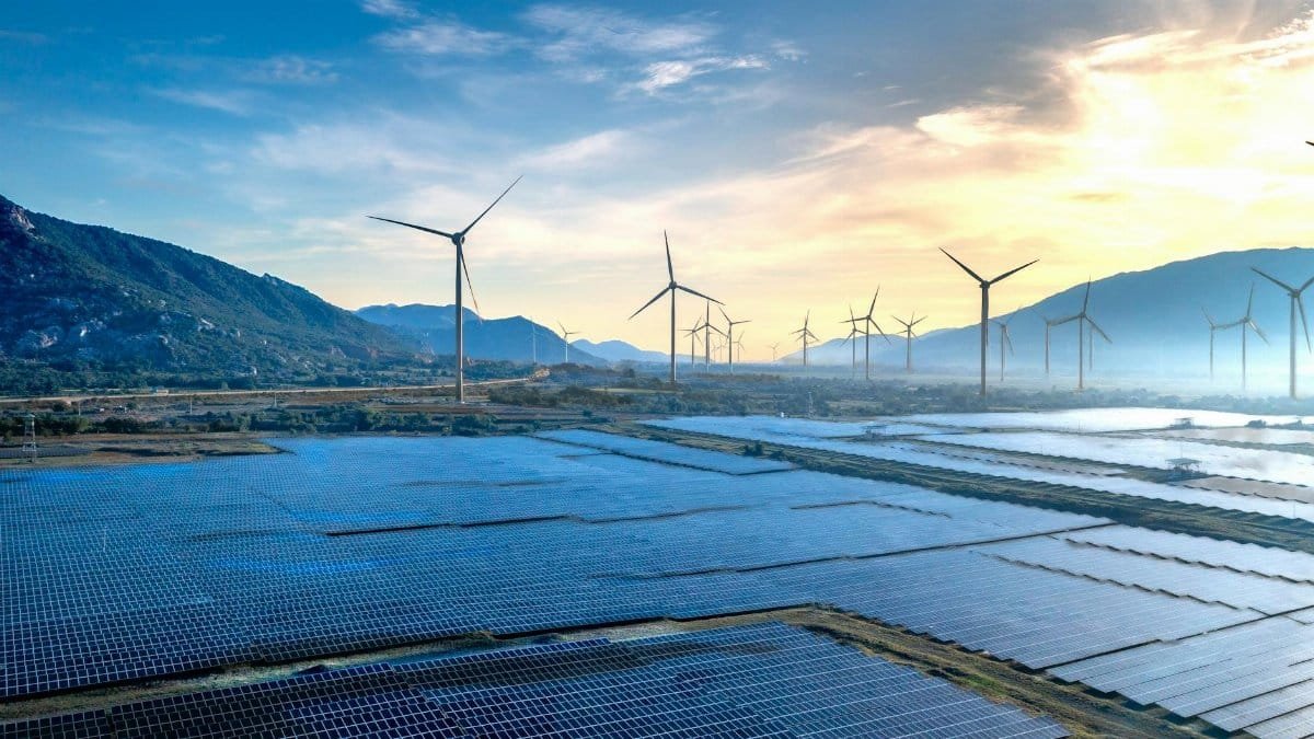 Stunning landscape featuring solar panels and wind turbines at sunrise, symbolizing sustainable energy.