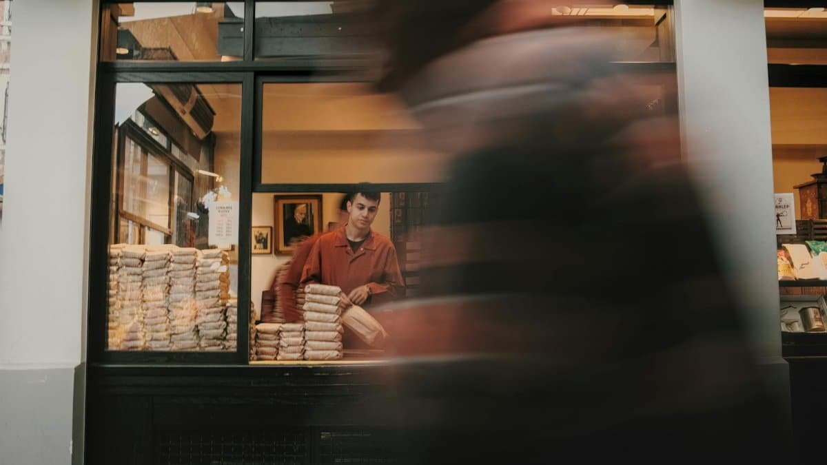 Street vendor sells products while a blurred pedestrian passes by, creating a dynamic urban scene.