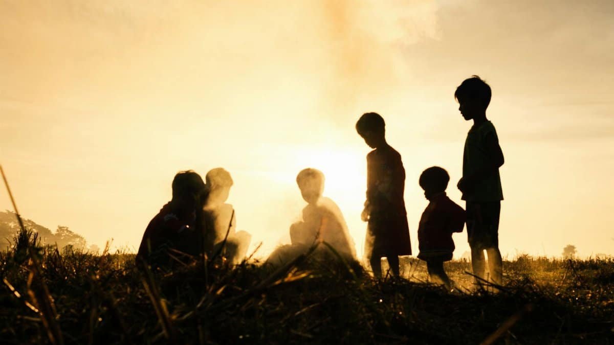 Silhouettes of children playing at sunset in Battambang Province, capturing a golden Cambodian evening.