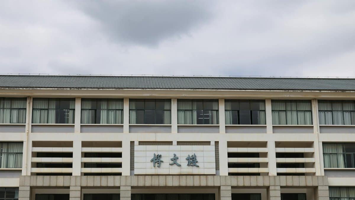 Front view of a modern educational building with Asian architectural elements under a cloudy sky.