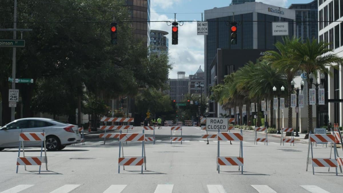 A downtown city intersection with road closures, traffic lights, and tall buildings.