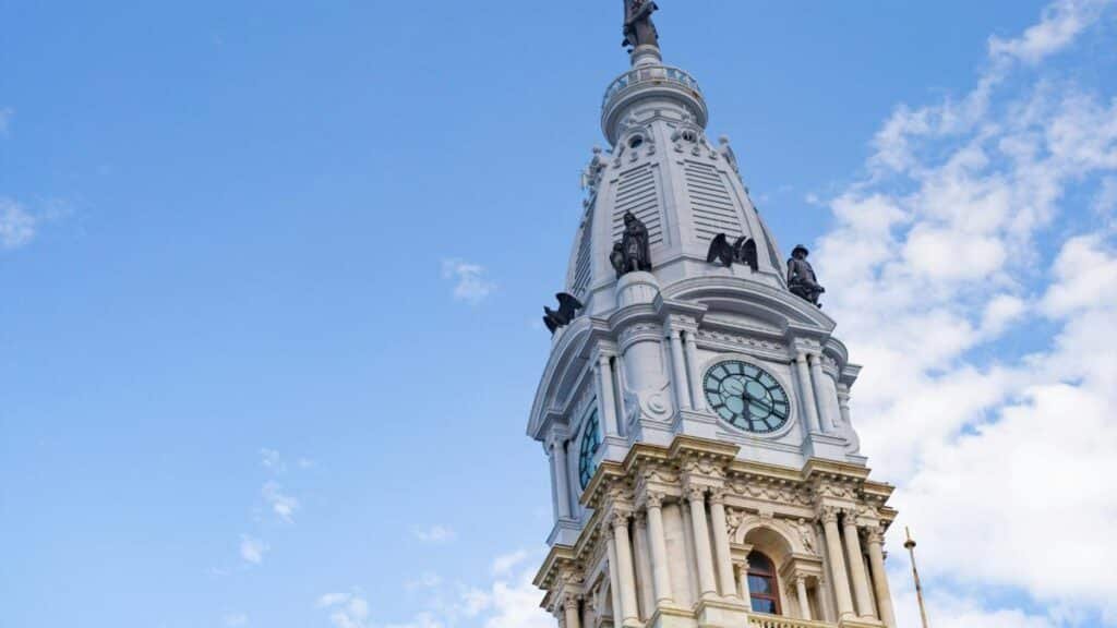 Iconic Philadelphia City Hall clock tower captured from a low angle against a clear blue sky.