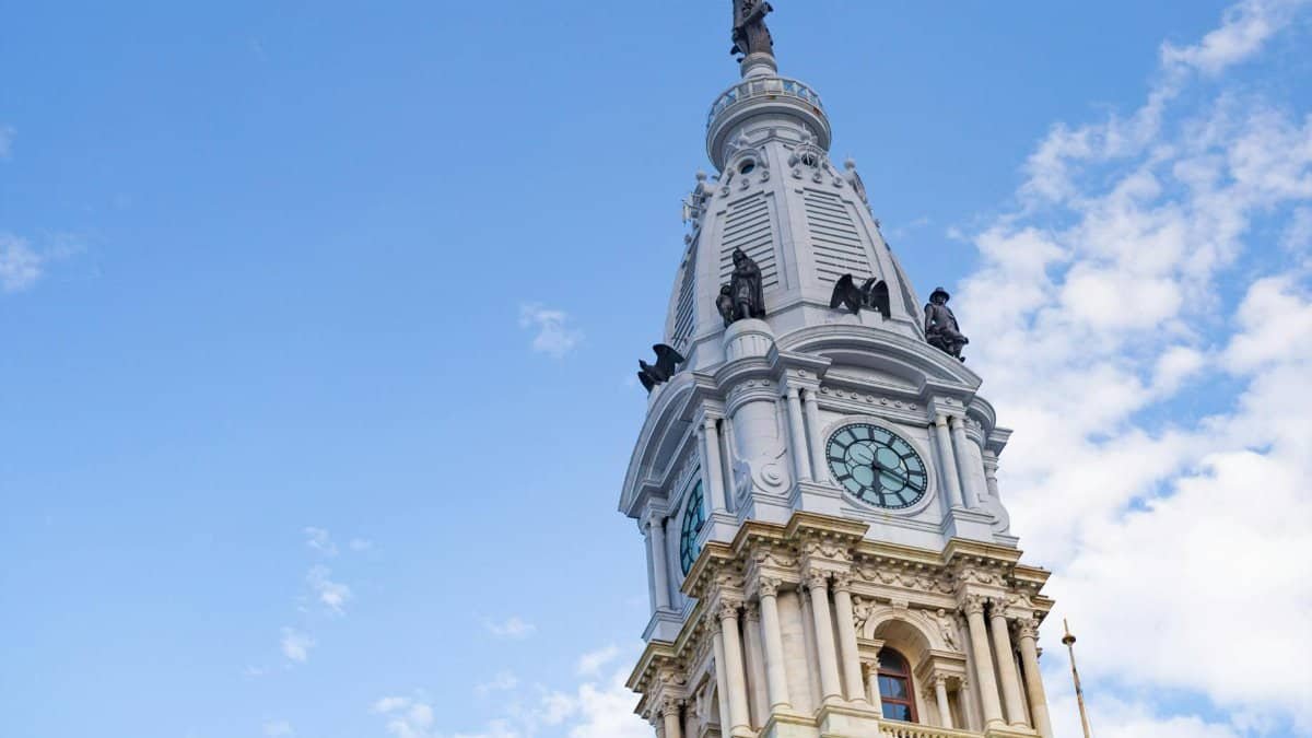 Iconic Philadelphia City Hall clock tower captured from a low angle against a clear blue sky.