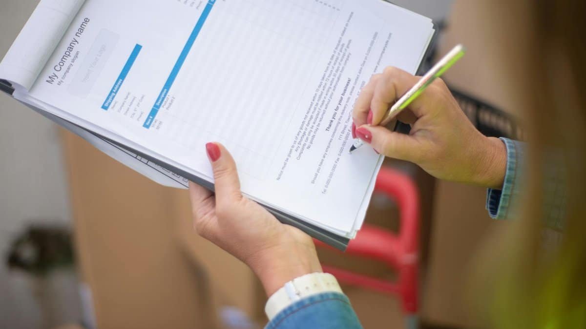 Close-up of woman's hand signing a document on a clipboard. Ideal for business and legal themes.
