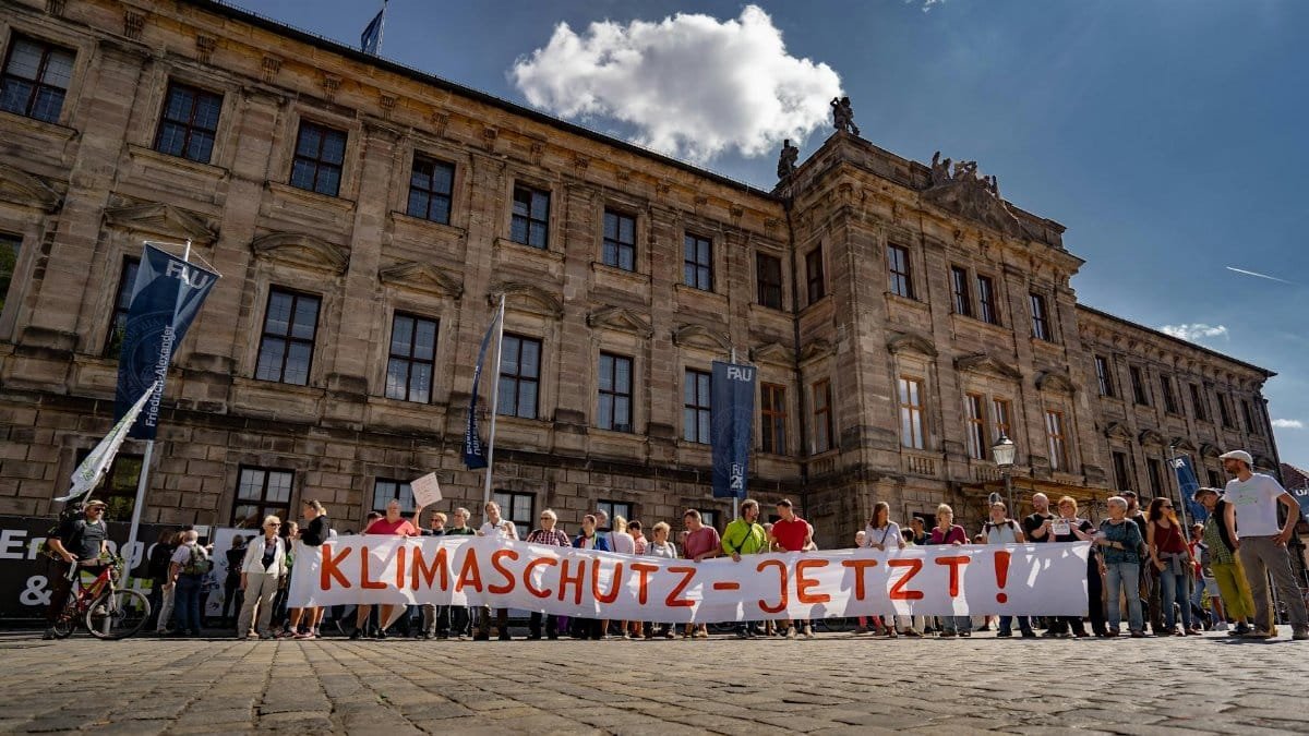 A group of activists rally for climate action outside a historic university building in Erlangen, Germany.