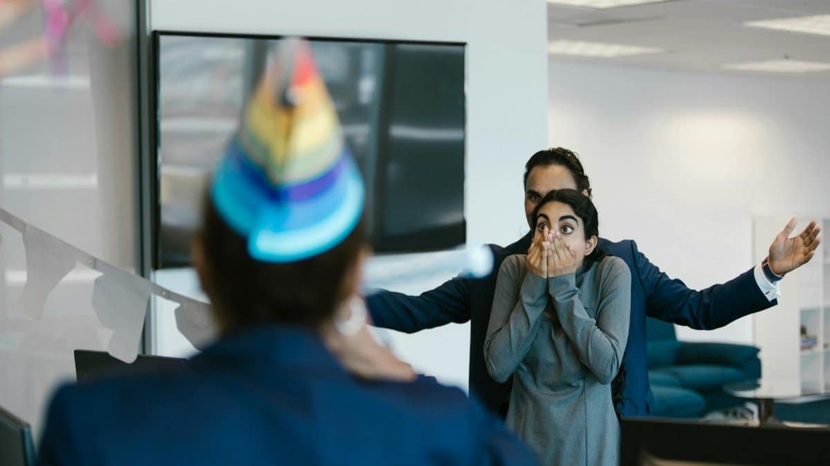 A surprised woman at an office party celebration with colleagues.