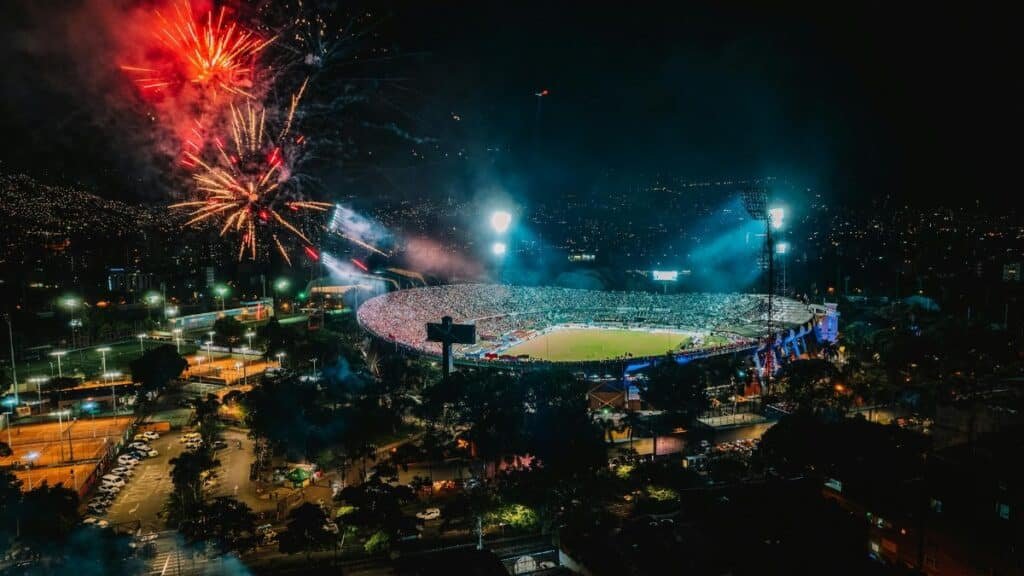A vibrant display of fireworks over a packed stadium in Medellín, Colombia, creating a festive atmosphere.